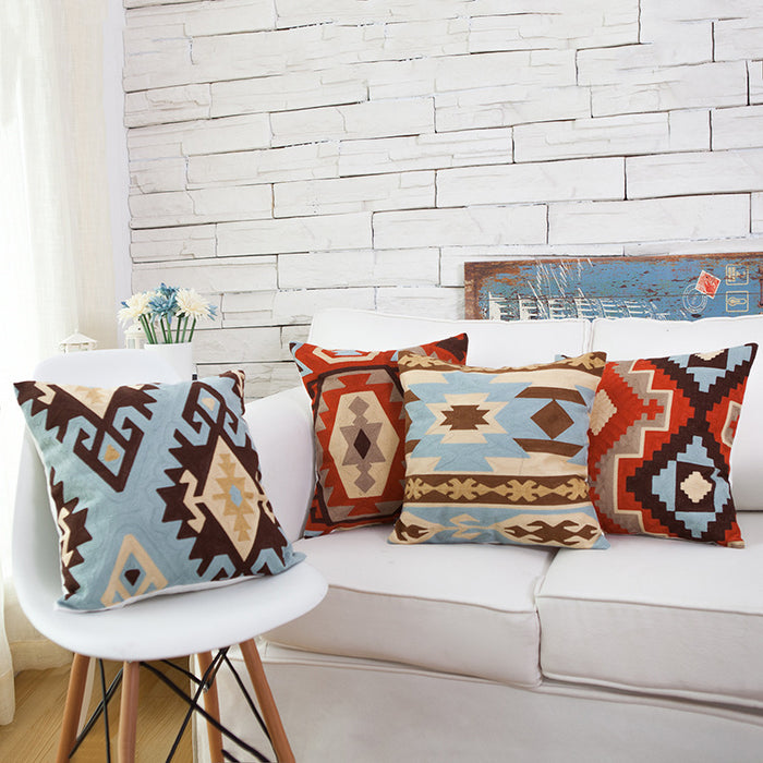 Set of decorative Southwestern throw pillows with geometric tribal embroidery in rust orange, sky blue, and brown for sofa decor.